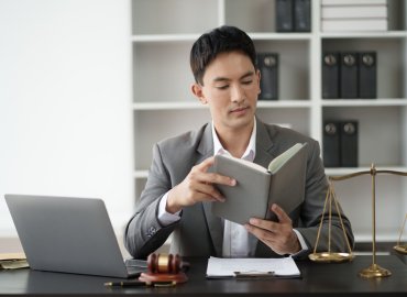 Asian professional lawyer reading books, studying about the case in his office room.